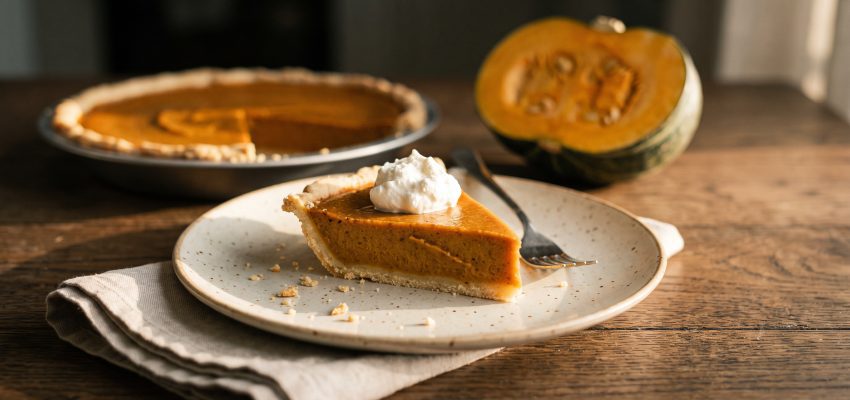 Porción de tarta de calabaza low FODMAP con un poco de nata montada sin lactosa sobre una mesa de roble oscuro
