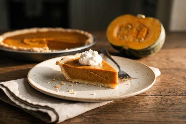 Punt low FODMAP pompoentaart met een toefje lactosevrije slagroom op een donkere eikenhouten tafel